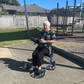 Woman using a walker in an outdoor setting with playground equipment in the background