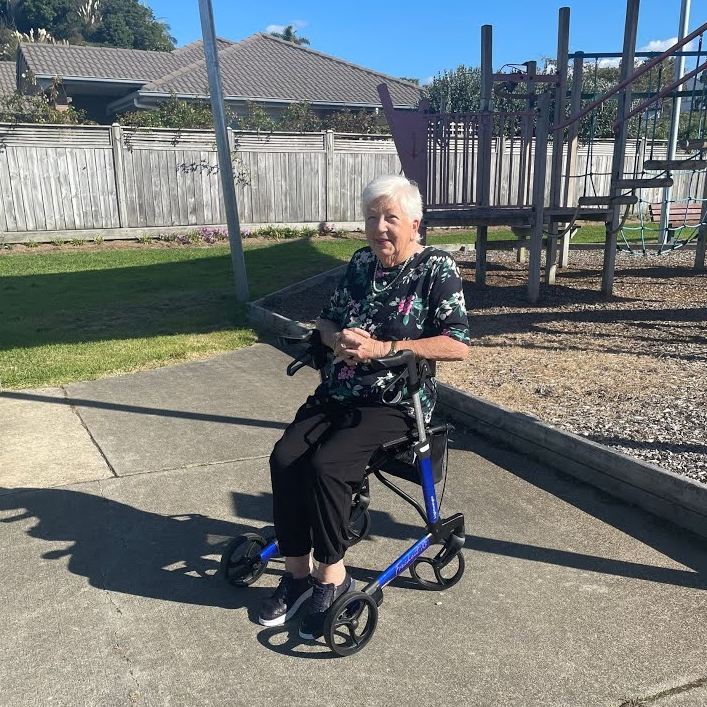 Woman using a walker in an outdoor setting with playground equipment in the background