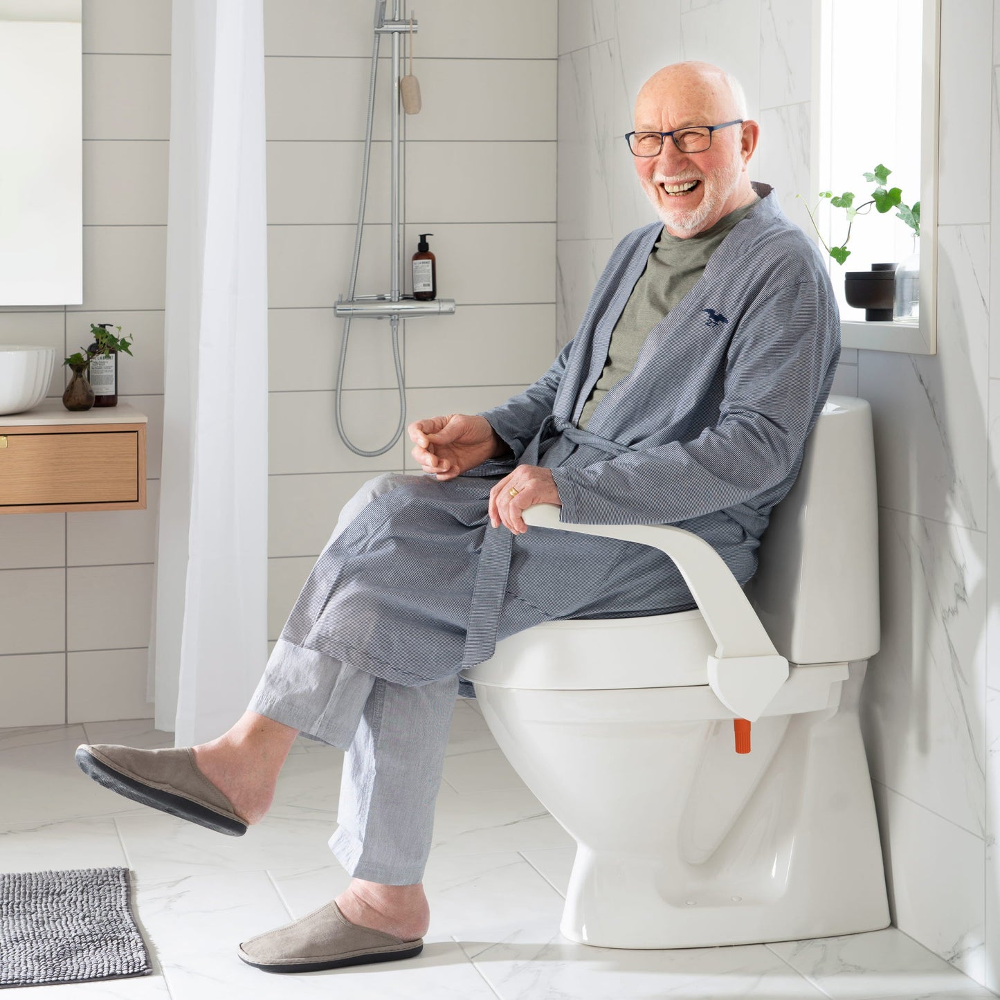 Man using Etac My-loo raised toilet seat in a modern bathroom.