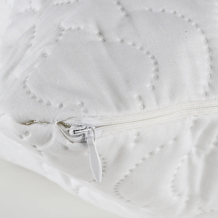 Close-up of a white quilted product with a zipper, on a light background.
